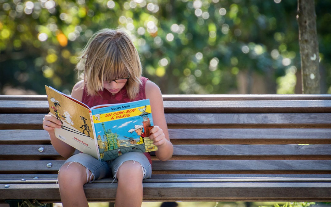 Kinder Medien: Das Foto zeigt einen Jungen, der auf einer Bank sitzt und ein Buch liest.